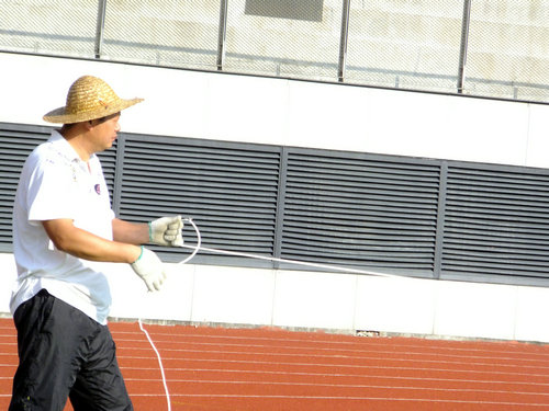 实拍深圳宝安体育馆足球场景观，有工人在维护有市民在跑步